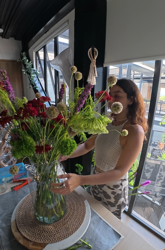 Participante creando una composición floral durante un taller en el atelier